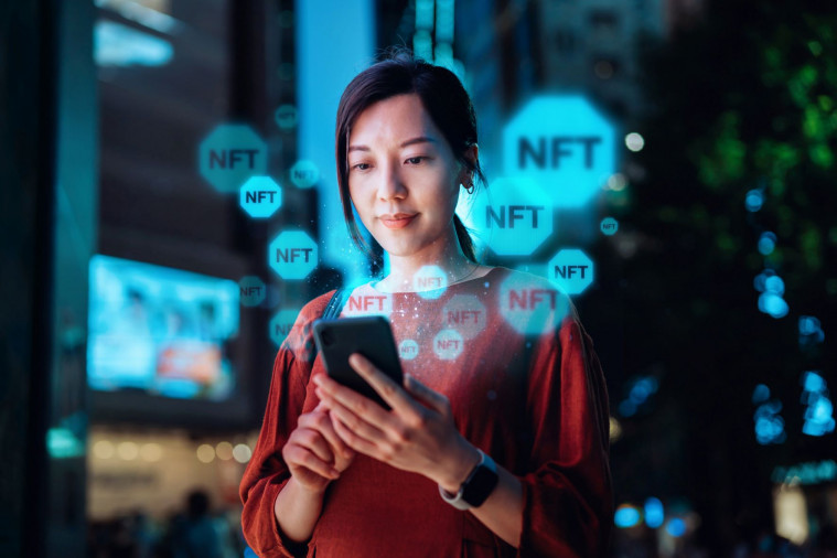 Jeune femme regardant un téléphone avec écrit NFT.

Young Asian woman using smartphone in downtown city street at night, working with blockchain technologies, investing or trading NFT (Non-Fungible Token) on cryptocurrency, digital asset, art work and digital ledger